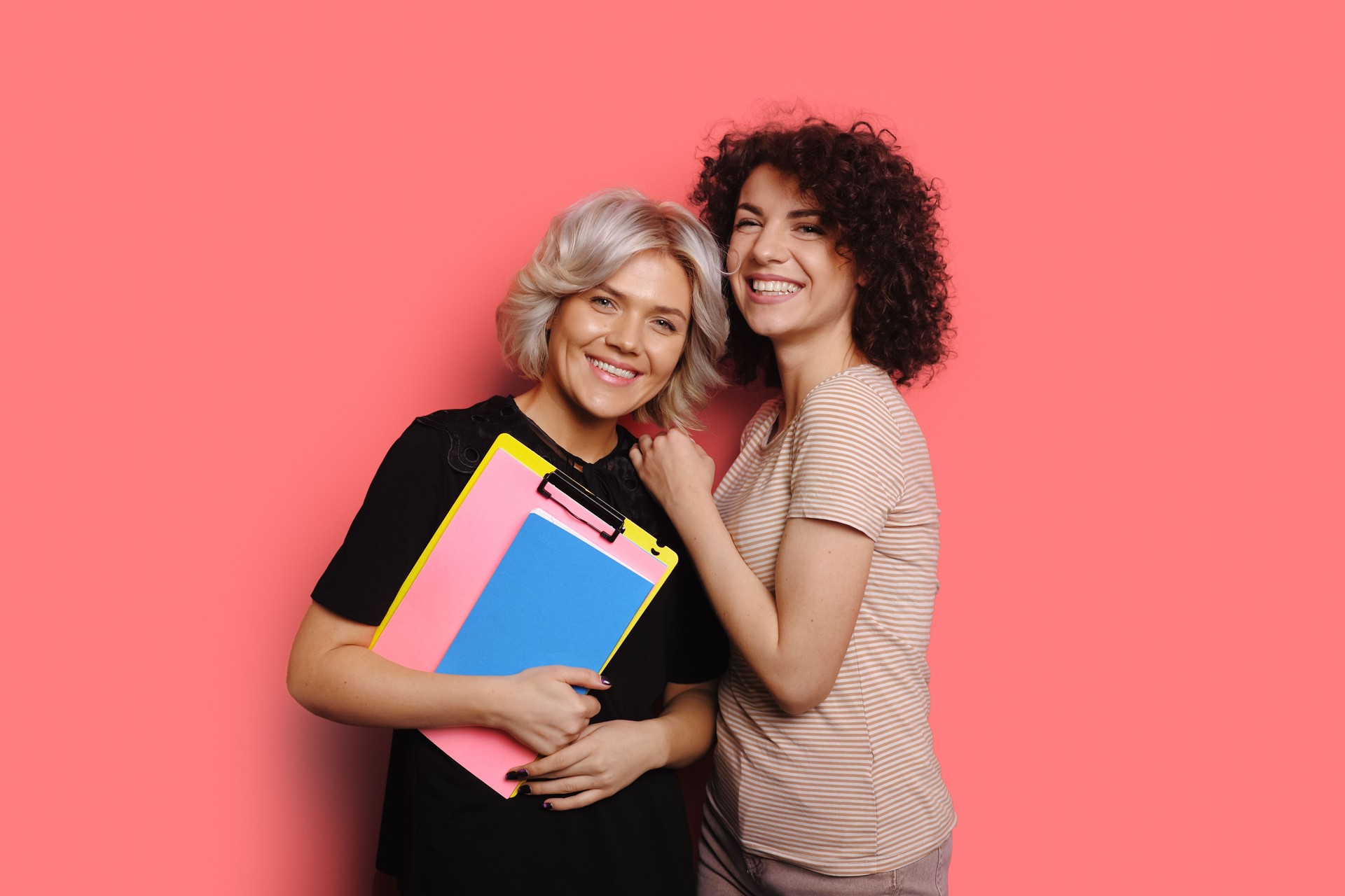 Stylish portrait of curly sister holding school folders. Pretty young woman. Happy family concept.
